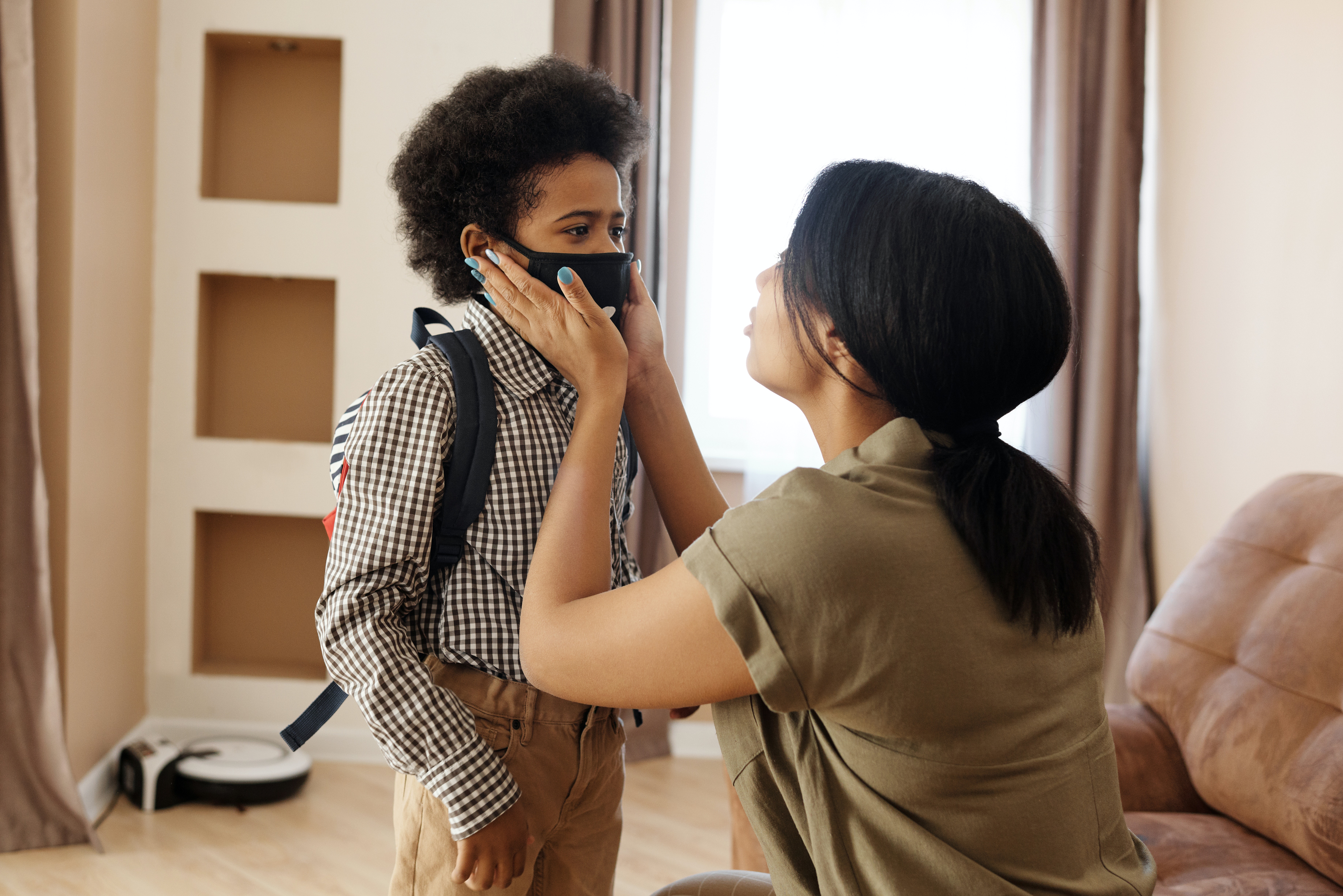 mother putting a face mask on her son